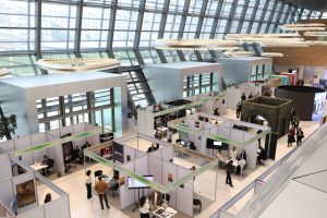 A bustling trade show exhibition inside a modern hall with people networking and exploring booths.